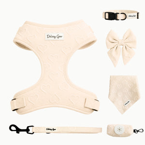 Collection of beige pet accessories including a harness, collar, bow tie, and bandana on a white background.