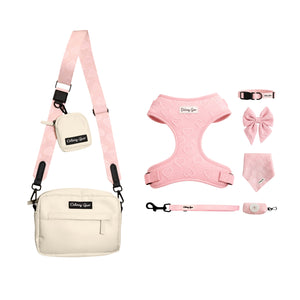A pet accessory set in pink and cream, including a matching crossbody bag, harness, leash, bandana, bow, collar, and clip, all branded with 'Daisy Go'.